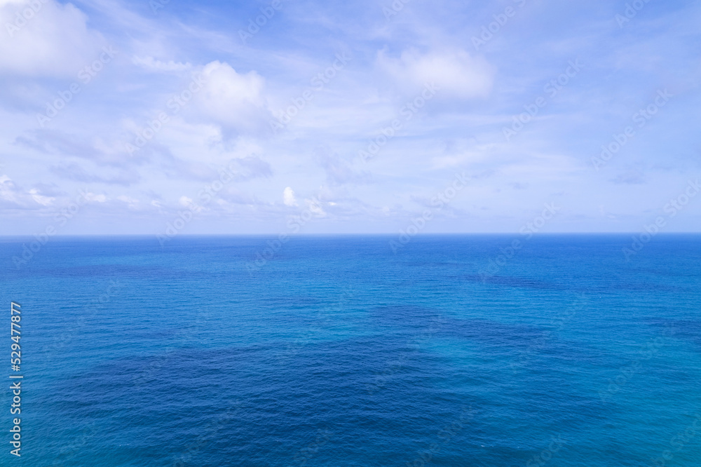 Aerial view of a blue sea water background and sun reflections. Aerial flying drone view and shadow clouds on sea surface,water texture on ocean, Aerial photography. Birds eye view. Sea, sky, clouds
