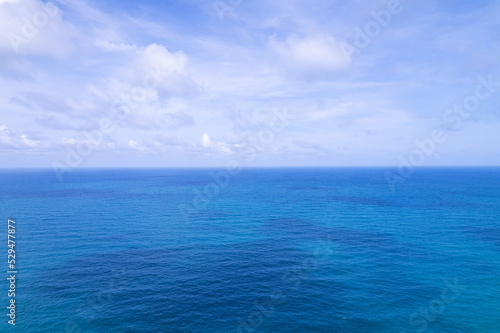 Aerial view of a blue sea water background and sun reflections. Aerial flying drone view and shadow clouds on sea surface,water texture on ocean, Aerial photography. Birds eye view. Sea, sky, clouds