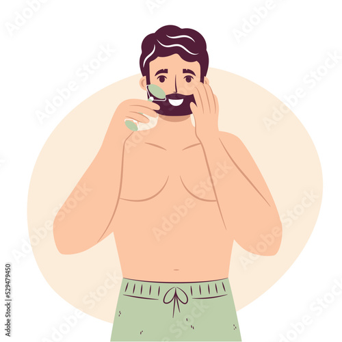 Skincare routine concept. Happy young man doing lymphatic face massage with face roller, handsome bearded male enjoying skincare procedure. Men hygiene