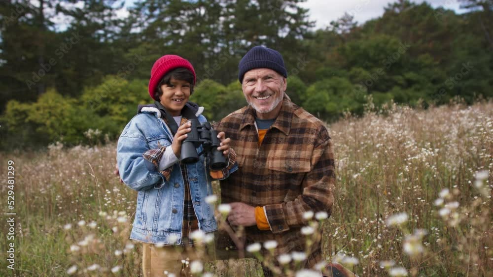 Senior man with his grandson resting at autumn meadow during camping.