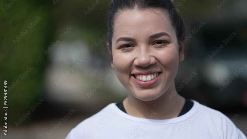 One happy Brazilian young woman walking forward in city street. A hispanic latin South American 20s girl walks in sidewalk One happy Brazilian young woman walking forward in city street. A hispanic latin South American 20s girl walks in sidewalk