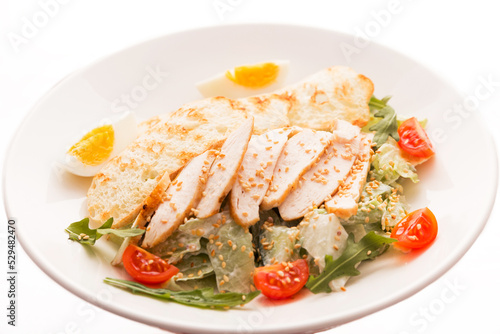 Caesar salad with chicken, white bread croutons, fresh lettuce, tomato and arugula on a white background