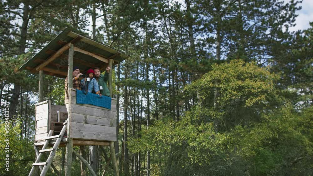 Grandfather, father and son having men time together in forest, sitting at high hunter seat drinking tea and observing nature. Grandfather, father and son having men time together in forest, sitting at high hunter seat drinking tea and observing nature.