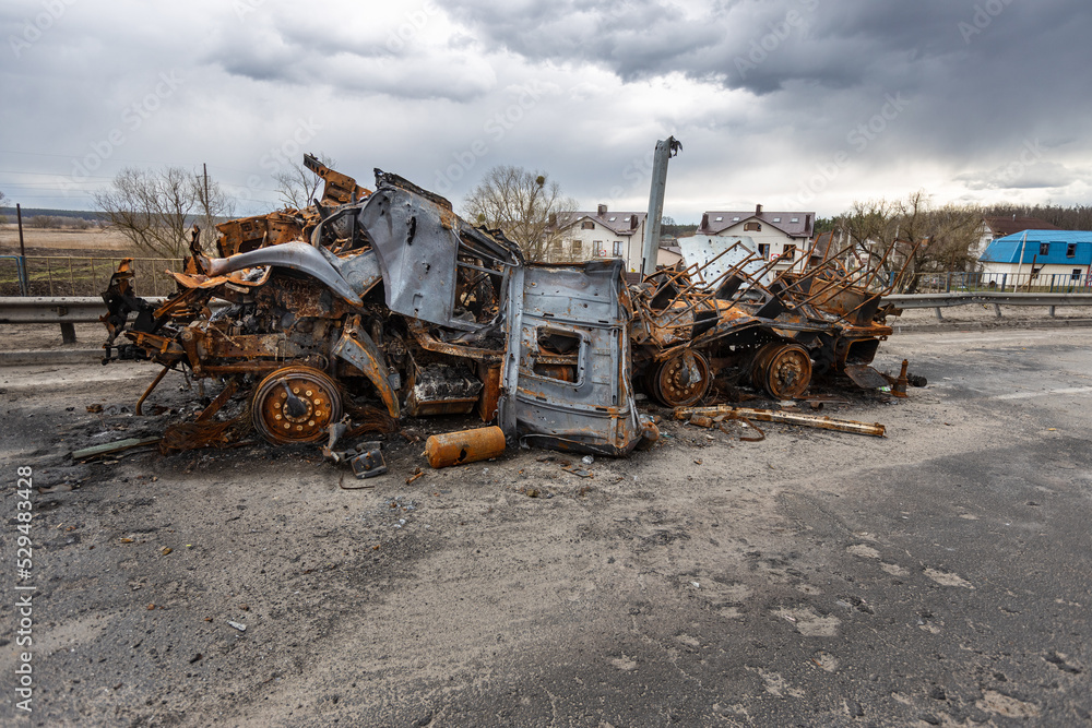 Fototapeta premium Hostomel, Kyev region Ukraine - 09.04.2022: Burnt military vehicles of Russian soldiers on the bridge across the river. Cars after being hit by rockets, mines. Rusty cars. Charred car parts.