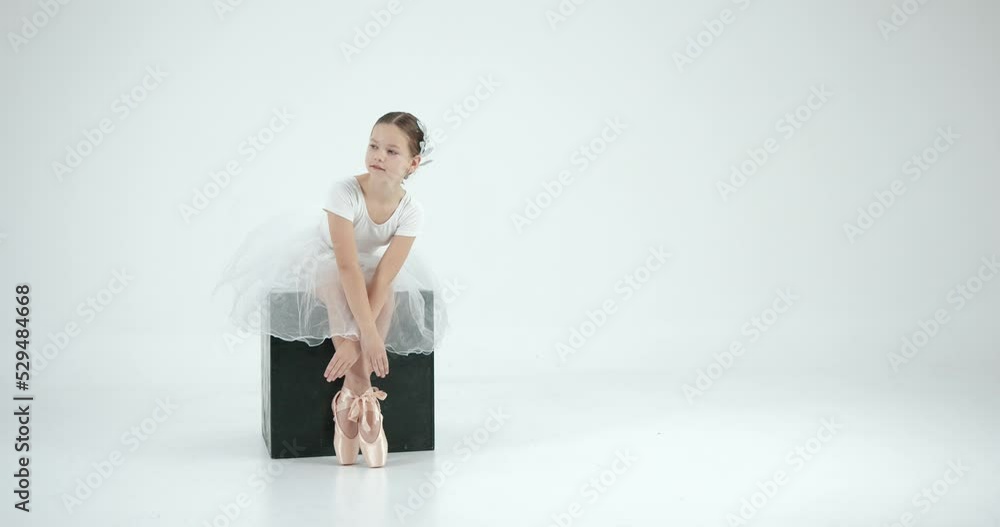 Little ballerinaposing on a black cube in studio Little ballerinaposing on a black cube in studio