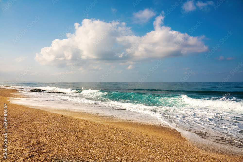 Beautiful calm natural seascape with a horizon line and clouds in blue sky, light surf and strip of golden sandy beach lit by sunlight. Beautiful calm natural seascape with a horizon line and clouds in blue sky, light surf and strip of golden sandy beach lit by sunlight.
