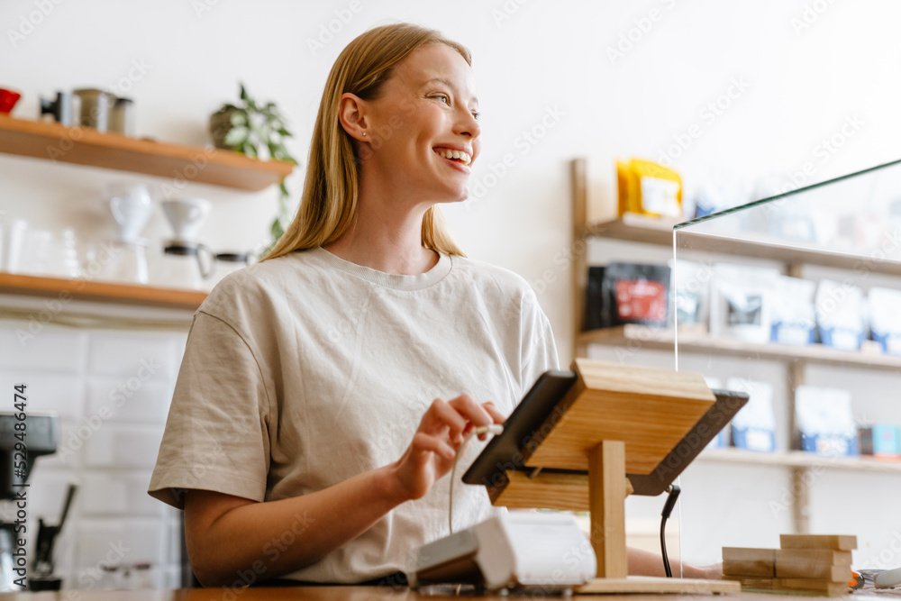 Blonde white barista woman working with tablet computer in cafe Blonde white barista woman working with tablet computer in cafe