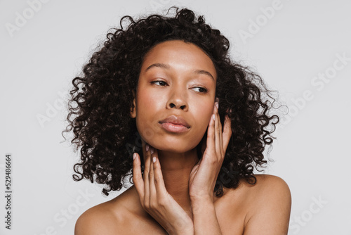 Black shirtless woman with curly hair posing and looking aside