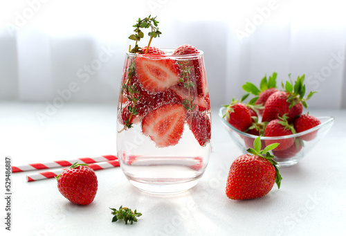 Detox strawberry thyme infused water or mocktail in a glass on white background