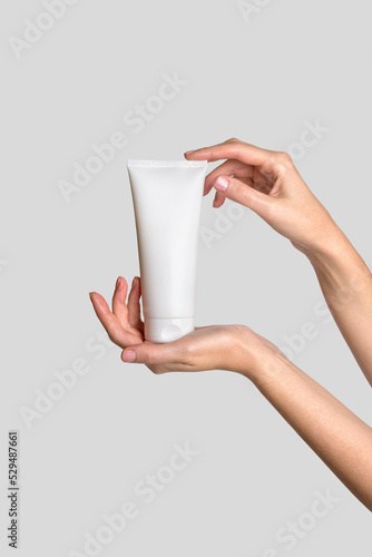 Woman hand showing cream product. Cosmetic product branding mockup. Daily skincare and body care routine. Female hand holding  cosmetic product mockup, close up.