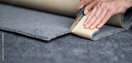 Handyman cutting a new carpet with a carpet cutter. photo