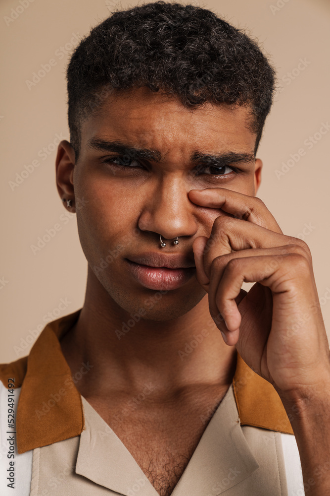 Young handsome crying african man looking at camera wiping tears