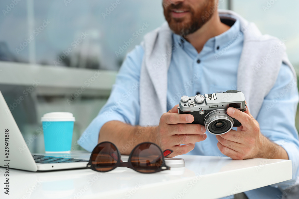 Man with camera, coffee and laptop in outdoor cafe, closeup. Interesting hobby Man with camera, coffee and laptop in outdoor cafe, closeup. Interesting hobby