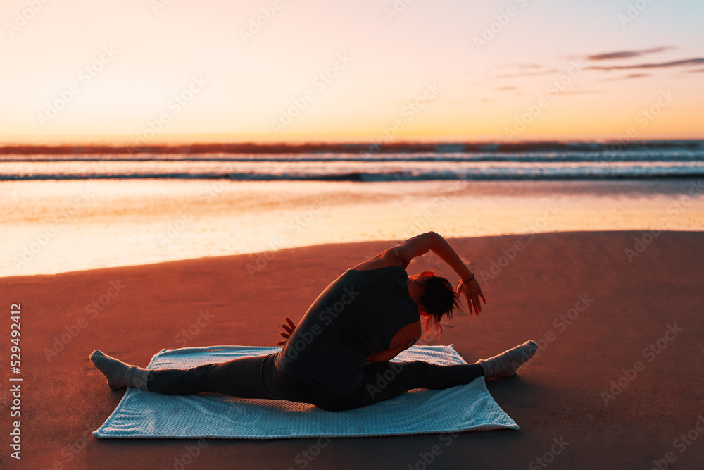 silhouette of a person on the shore of the beach practicing yoga or meditation at sunset