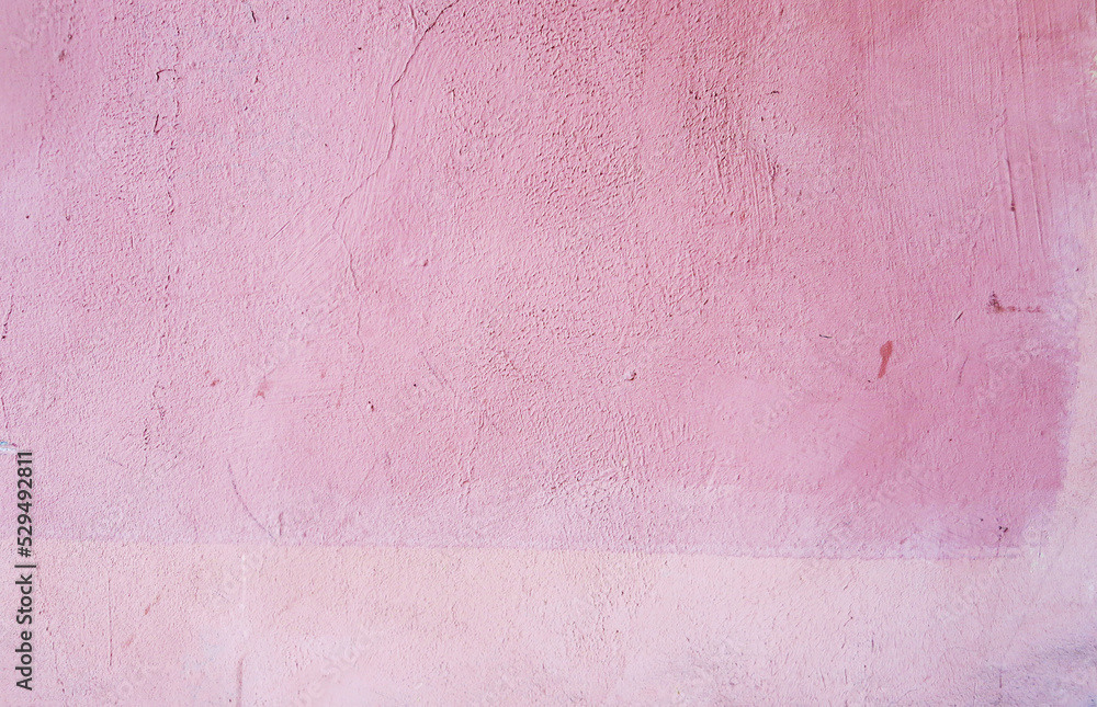 Plastered wall covered with pink paint. The wall of a city house. Pink background.