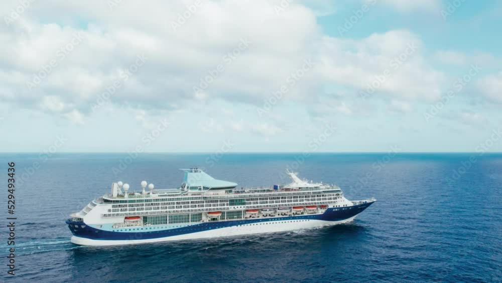 Orbit shot around large passenger cruise ship in sea at dramatic overcast weather with white clouds and blue sky. Orbit shot around large passenger cruise ship in sea at dramatic overcast weather with white clouds and blue sky.