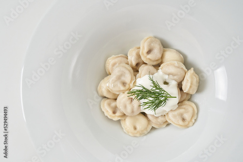 dumplings with sour cream with herbs on a white plate