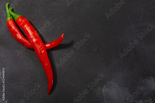Guajillo chile peppers atop black background, top view, copy space. Capsicum annuum fruits. Mexican chilies