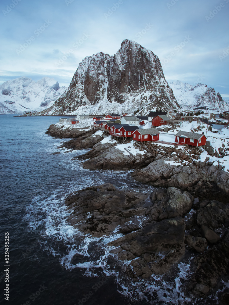 Famous location in Hamnoy in Lofoten. Fisherman's village in front of the wild sea and huge mountain covered by snow at winter season in Norway