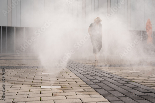silhouette of a person passing through the water curtain cooling the air on a hot summer day in Prague