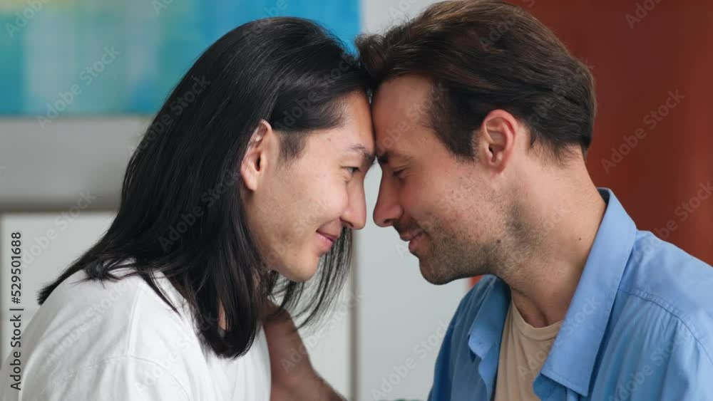 Closeup of diverse gay couple touching foreheads and look into each other eyes Closeup of diverse gay couple touching foreheads and look into each other eyes