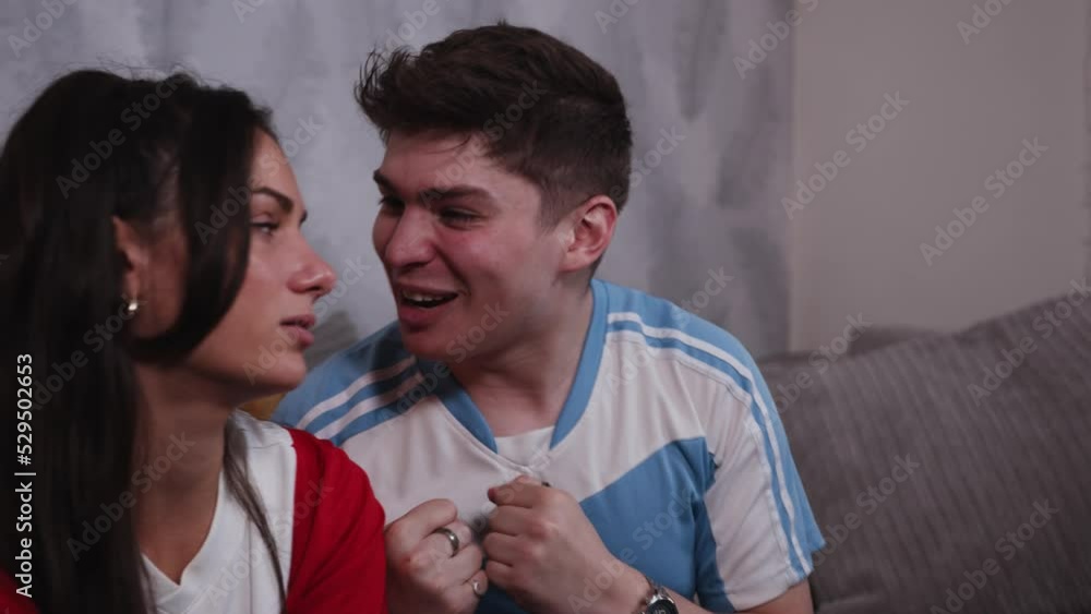 Rival fans watch football together male blue fan celebrates and gloats in slow motion close up