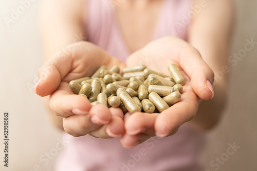 handful of green kratom pills in woman hands, no face, selective focus