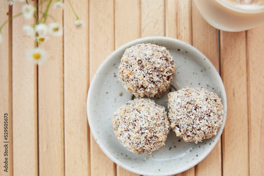 Vegan handmade delight - gluten and sugar free natural balls sweets and coffee on the wooden table close up. Healthy dessert. Raw food.