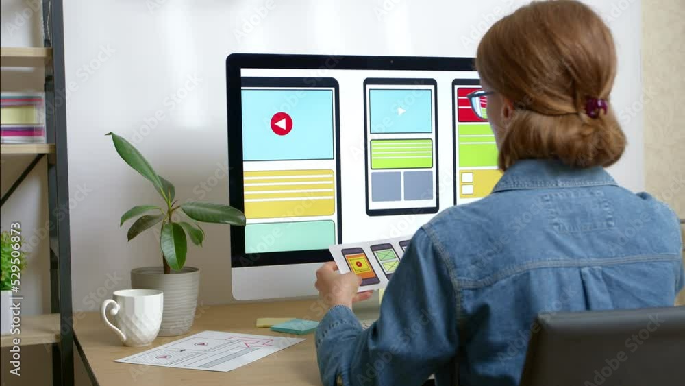 A woman web designer is working on the creation of an application interface for a mobile phone using a computer. User experience A woman web designer is working on the creation of an application interface for a mobile phone using a computer. User experience