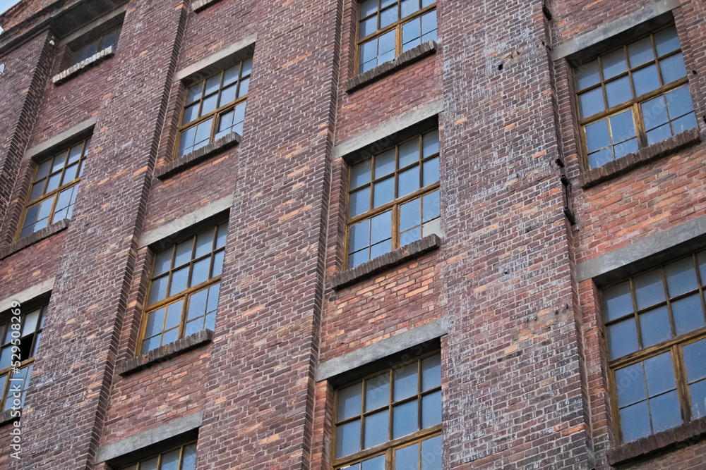 Obraz premium Red brick wall of an abandoned factory with windows.