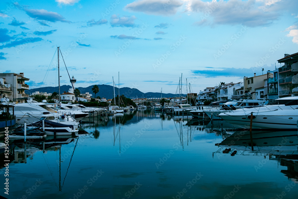 Empuriabrava spanish town in view of main water channel with boats at dusk. Landscape of the catalan town in the Costa Brava region known for its canals and marina
