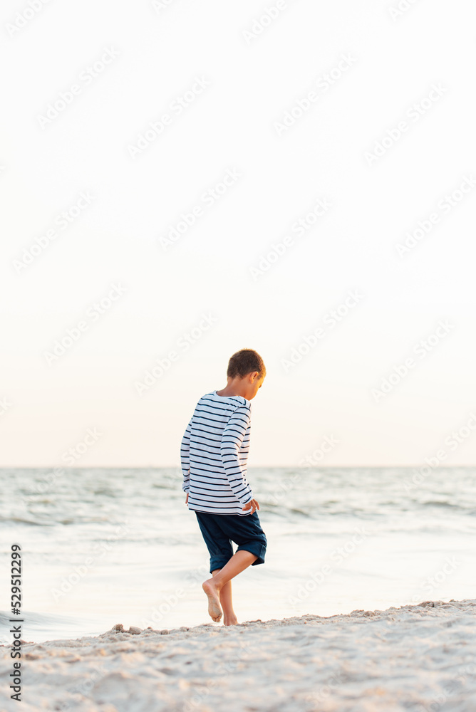 summer vacation at sea. Boy at seaside. Child collect shells on beach having fun during summer holiday. happy kid playing at sunset time. Happy childhood. Travel and adventure concept summer vacation at sea. Boy at seaside. Child collect shells on beach having fun during summer holiday. happy kid playing at sunset time. Happy childhood. Travel and adventure concept