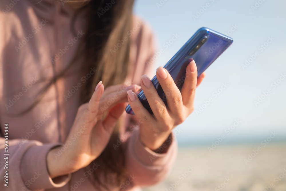 girl holding phone smartphone in hands on the seashore