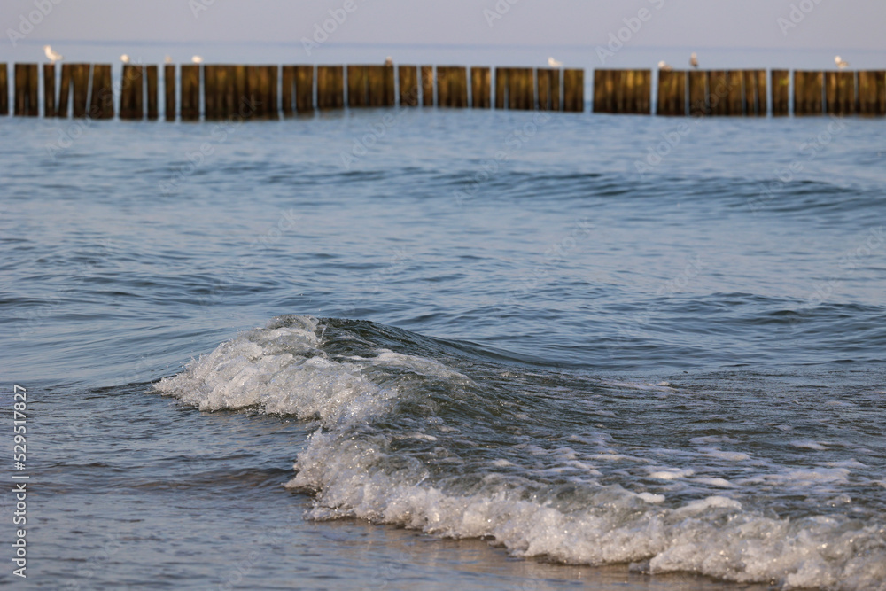 Widok na plażę z bałwanami fal morskich i bryzgami wody. - obrazy, fototapety, plakaty 