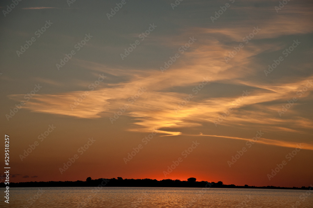 Sunset at the lagoon. The sky is orange and the lagoon marks the horizon line.