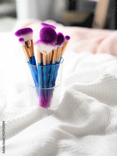 Fotomurale Vertical closeup shot of numerous purple and blue makeup brushes in a glass brus