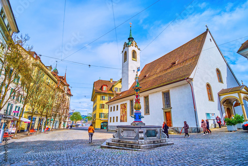 St. Peter's Chapel on Kapellplatz with colorful Fritschi Fountain in Lucerne, Switzerland