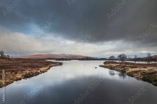 Minimal Winter landscape across Loch Ba in Rannoch Moor with stormy dramatic sky overhead
