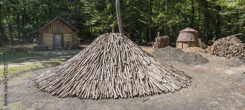 ancienne installation de production de charbon de bois au milieu d'une forêt avec un tas de bois prêt à être brulé