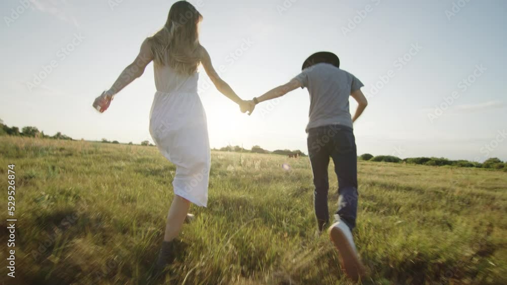 Cheerful beloved couple running and hugging on grassy field in countryside Cheerful beloved couple running and hugging on grassy field in countryside