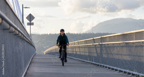 Caucasian Woman riding on a bicycle on a bike lane at Port Mann Bridge. Greater Vancouver, British Columbia, Canada.