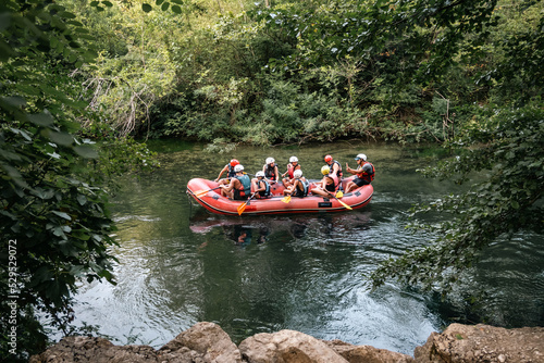 Group of tourists taking rafting tour on the Cetina river, listening to the information from the instructor in the dinghy © Miroslav Posavec