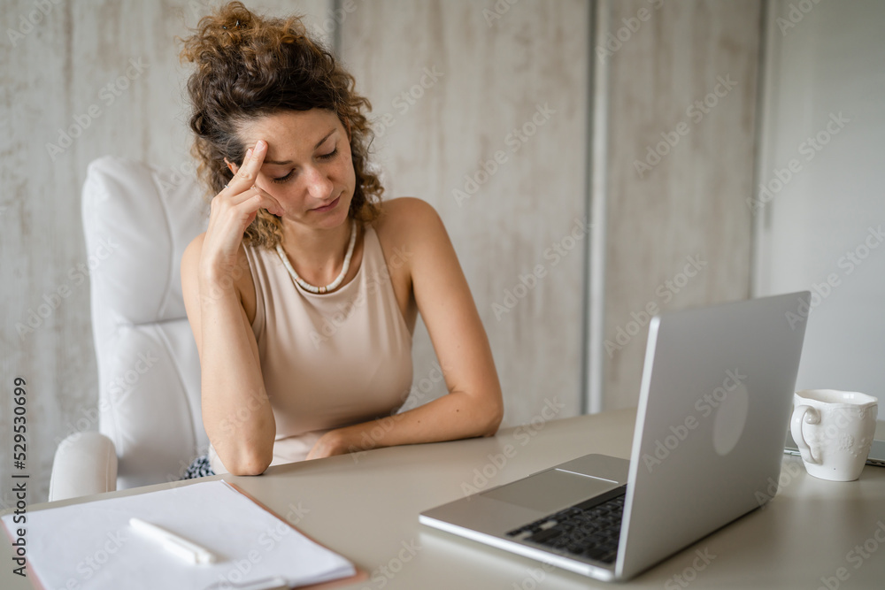 One young woman caucasian female sitting and thinking in the office One young woman caucasian female sitting and thinking in the office