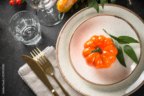 Autumn table setting with plate, cutlery, pumpkin. Thanksgiving food festive dinner. Top view at black table. photo