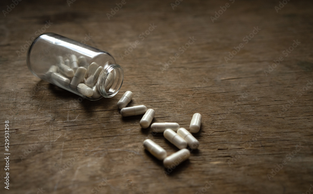 A bottle of pills scattered on a wooden table. Overdose with medications. Narcotic pills. A bottle of pills scattered on a wooden table. Overdose with medications. Narcotic pills.