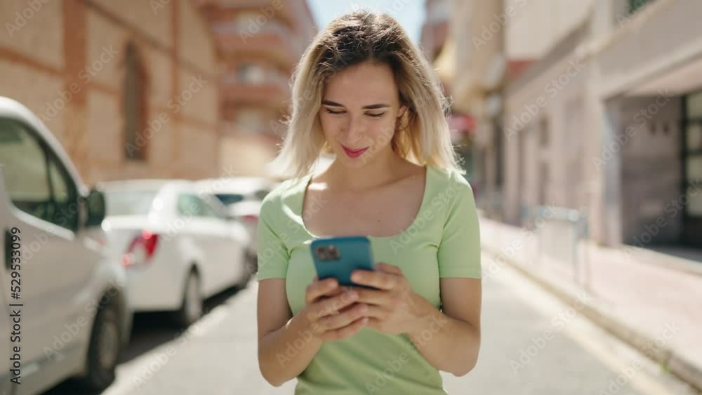 Young woman smiling confident using smartphone walking at street Young woman smiling confident using smartphone walking at street