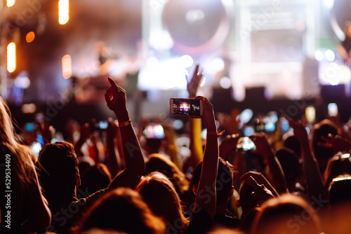 Using a smartphone in a public event, live music festival. Summer holiday, vacation concept. 