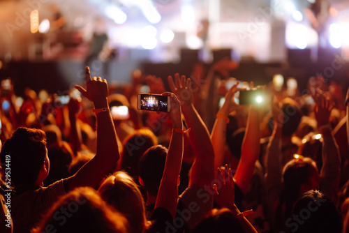 Using a smartphone in a public event, live music festival. Summer holiday, vacation concept. 