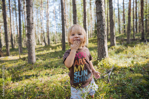 Blond Baby girl picking and eating berries in the forest 