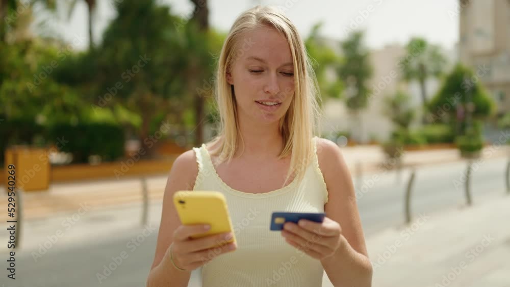 Young blonde woman using smartphone and credit card at park Young blonde woman using smartphone and credit card at park